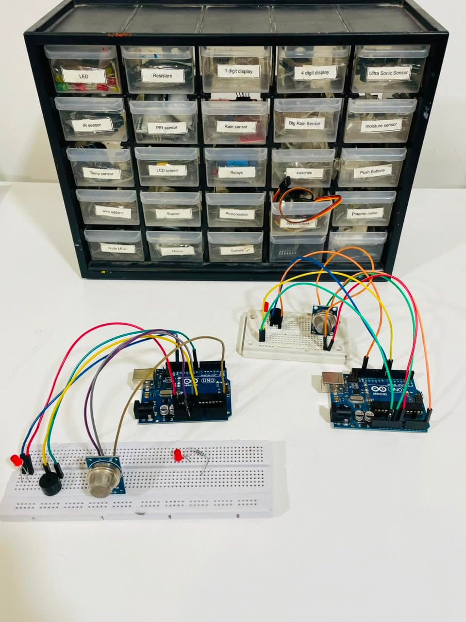 A labelled electronics kit with two Arduino boards and an MQ-2 gas sensor wired on breadboards